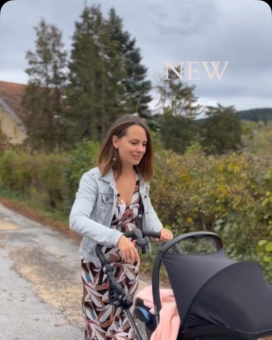 Léa en robe Lola, veste en jean, pousse une poussette sur un chemin, extrait du reel « un doux moment de maternité », printemps 2025