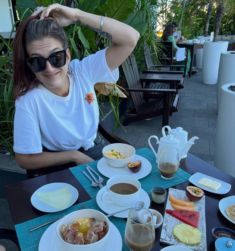 Léa en terrasse au petit-déjeuner, lunettes de soleil et tee-shirt blanc à la fleur, août 2026